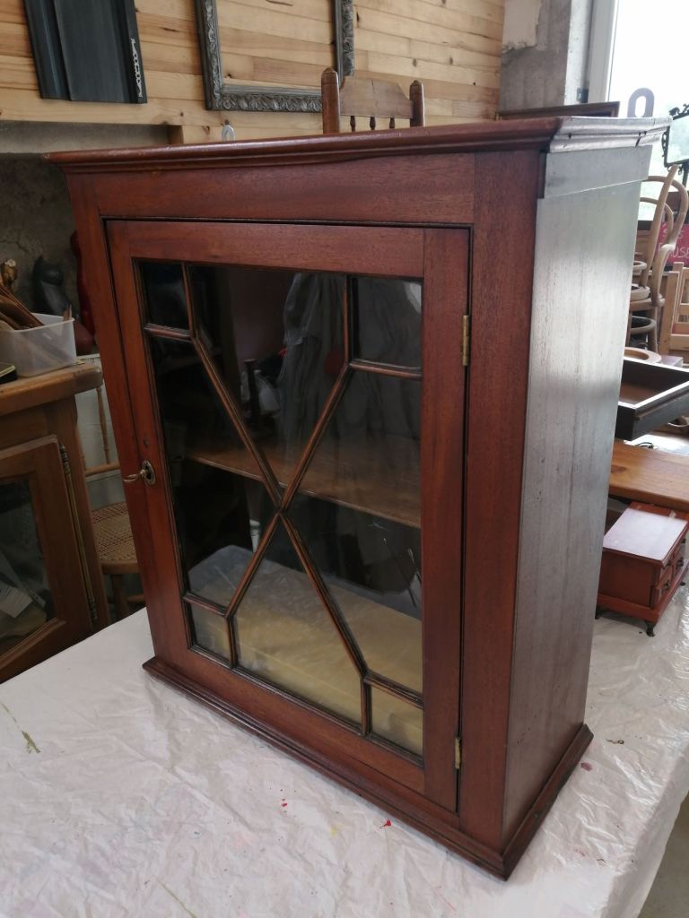 A vintage wooden display cabinet with glass doors and a diamond pattern design, showcasing its elegant craftsmanship.