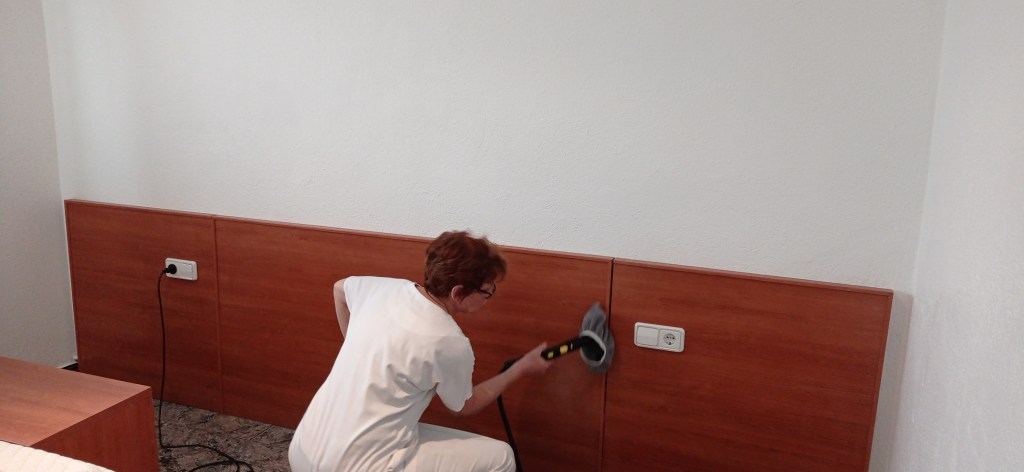 A person cleaning a wooden wall panel with a cleaning tool in a room.