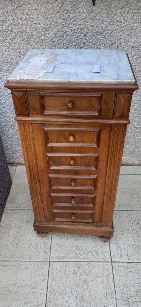 Wooden chest of drawers with a marble top and six smaller drawers, displayed on a tiled floor.
